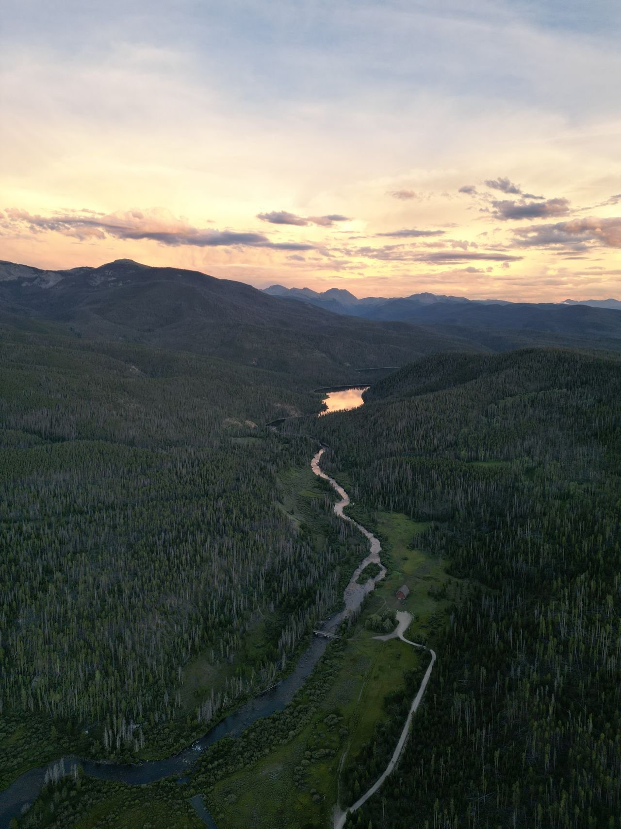 Colorado mountain valley with a river winding through evergreen forest at golden hour